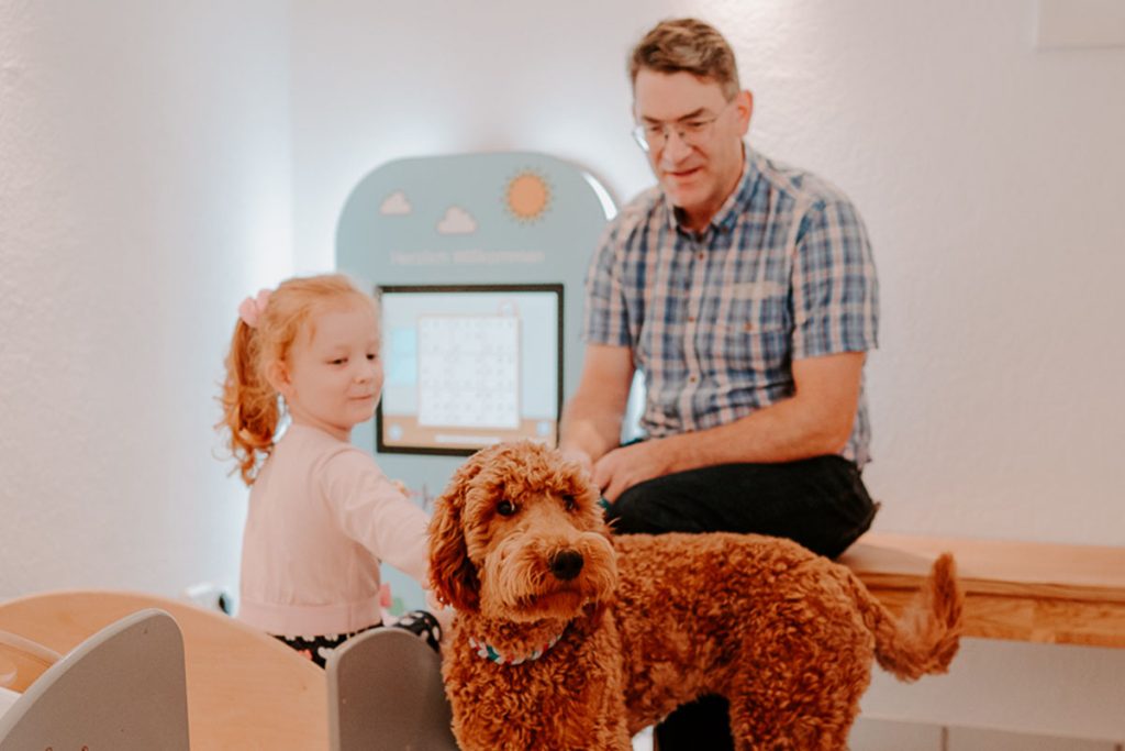 Ein Kind streichelt Therapiehund Luna in Anwesenheit eines Mannes beim Zahnarzt in Einbeck