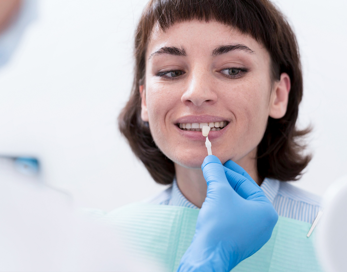Patientin bei der Auswahl der Zahnfarbe für keramische Veneers in der Zahnarztpraxis